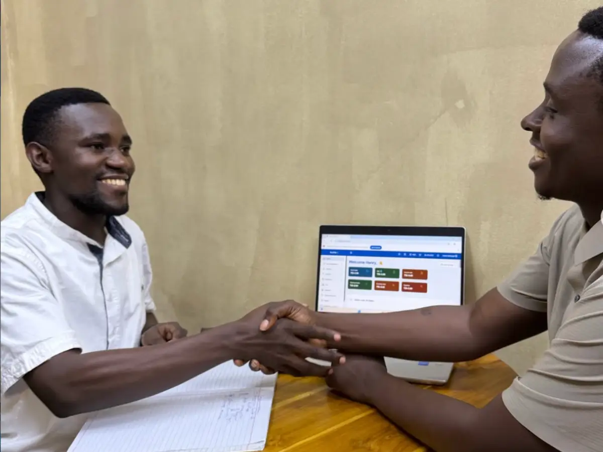 An iPAB consultant and a client shaking hands over a laptop running the system
